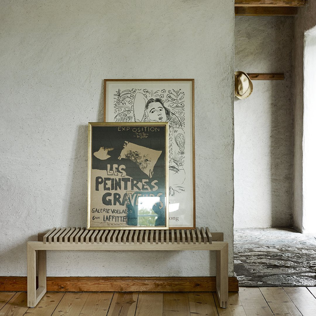 Elegant wooden bench with a slatted design, complementing neutral wall tones and vintage black-and-white art.