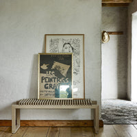 Elegant wooden bench with a slatted design, complementing neutral wall tones and vintage black-and-white art.