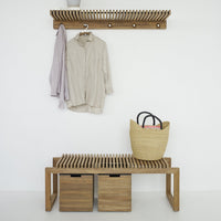 Wooden bench with slatted design, natural oak color, paired with neutral beige hanger and straw basket.