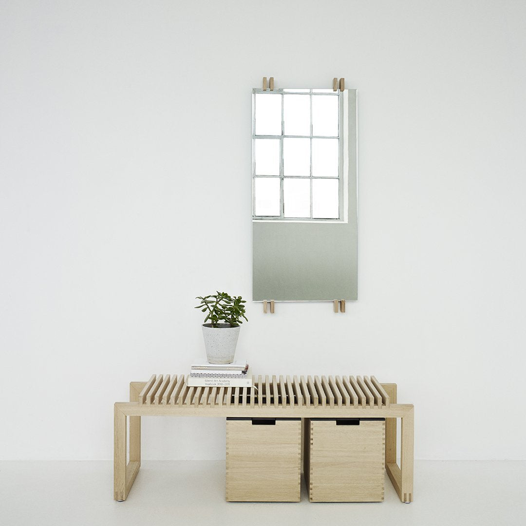 Natural wood tones with a minimalist design; features a sleek, rectangular mirror against a white wall.