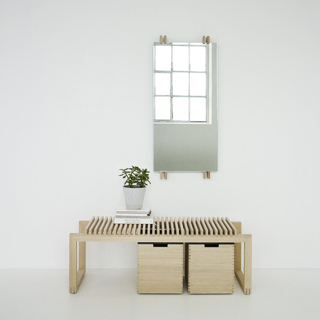 Light wood bench with slatted design, two storage boxes, and a minimalist mirror above, creating a calm, neutral aesthetic.