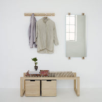 Neutral-toned shirt hanging on a wooden rack, paired with soft gray layers and natural wood furniture accents.