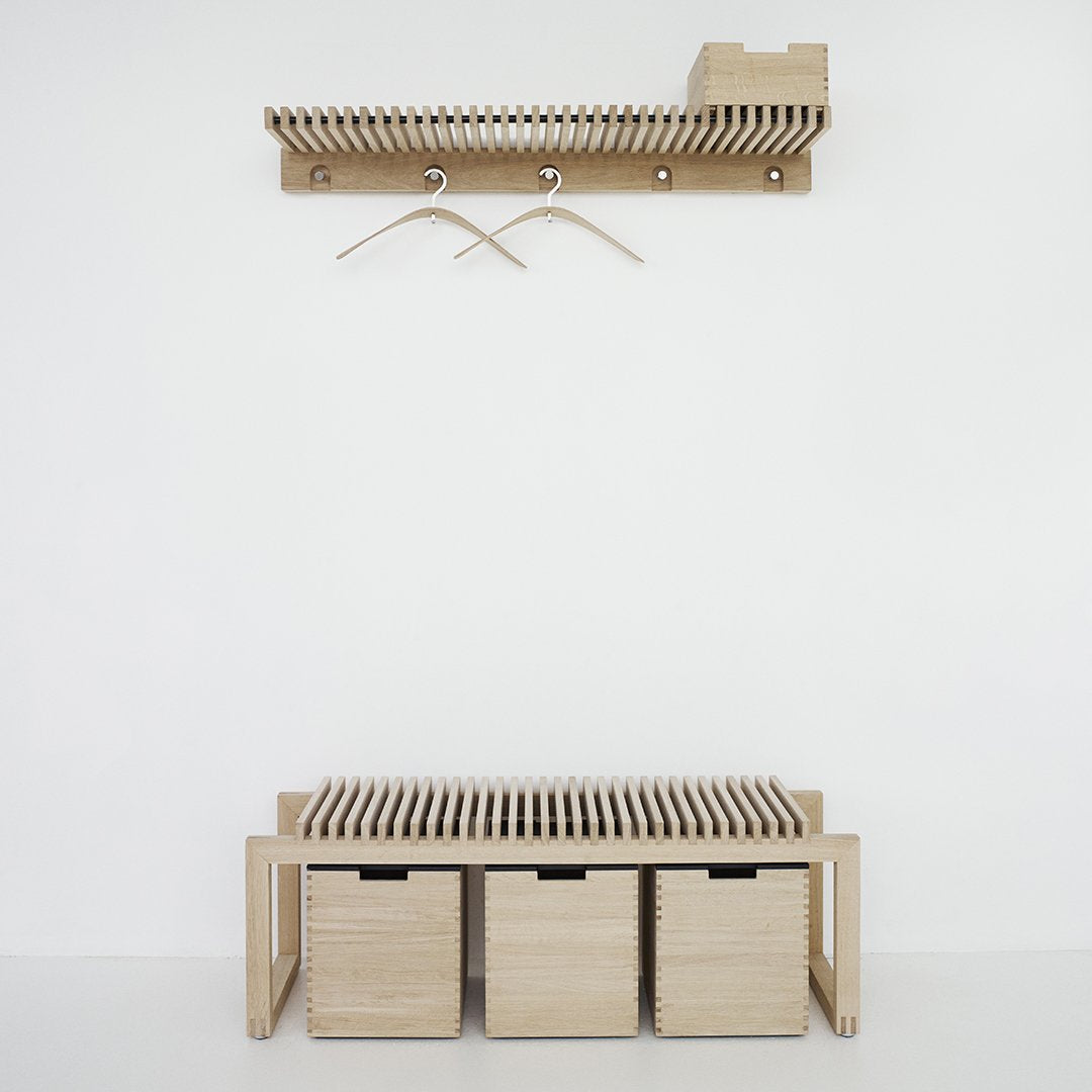 Light wood storage bench with three cube drawers and a matching wall-mounted coat rack in a minimalist design.