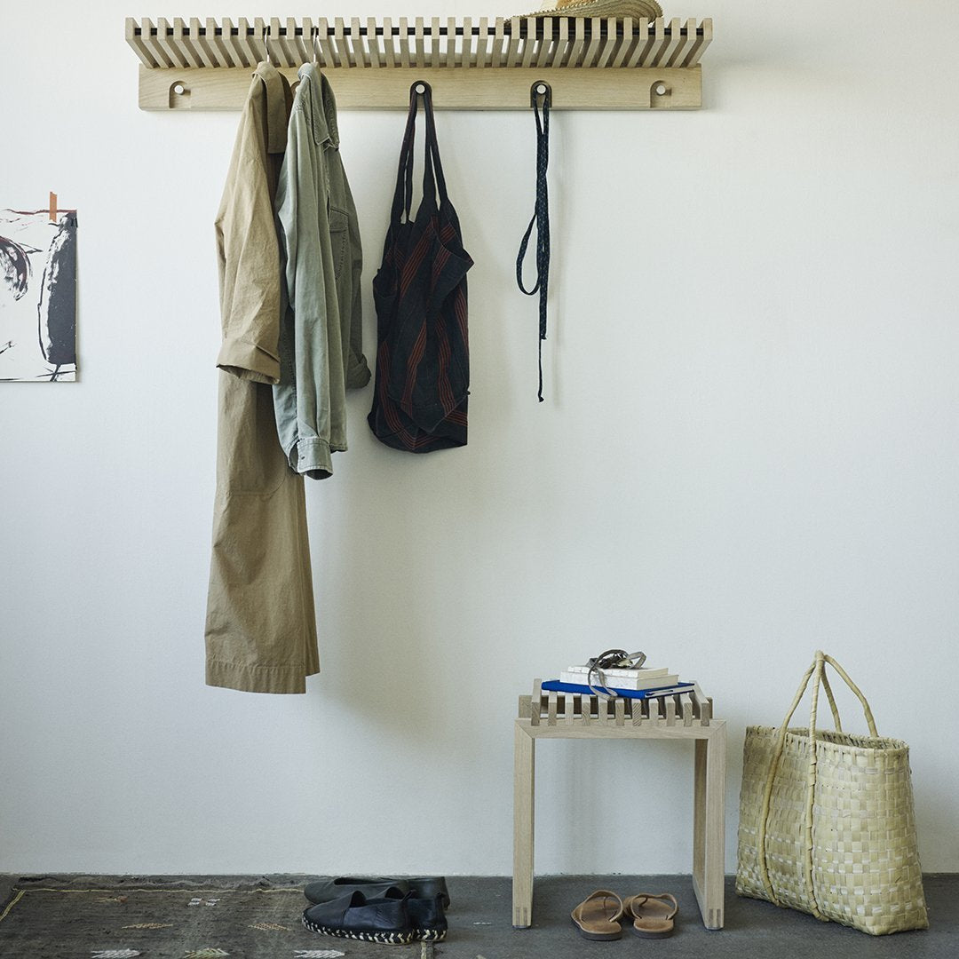 "Neutral tones with olive green, black, and beige patterns showcased in a stylish organized entryway setup."