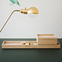 Natural wood tray with smooth grain, featuring light wood tones and a minimalist design on a dark green surface.