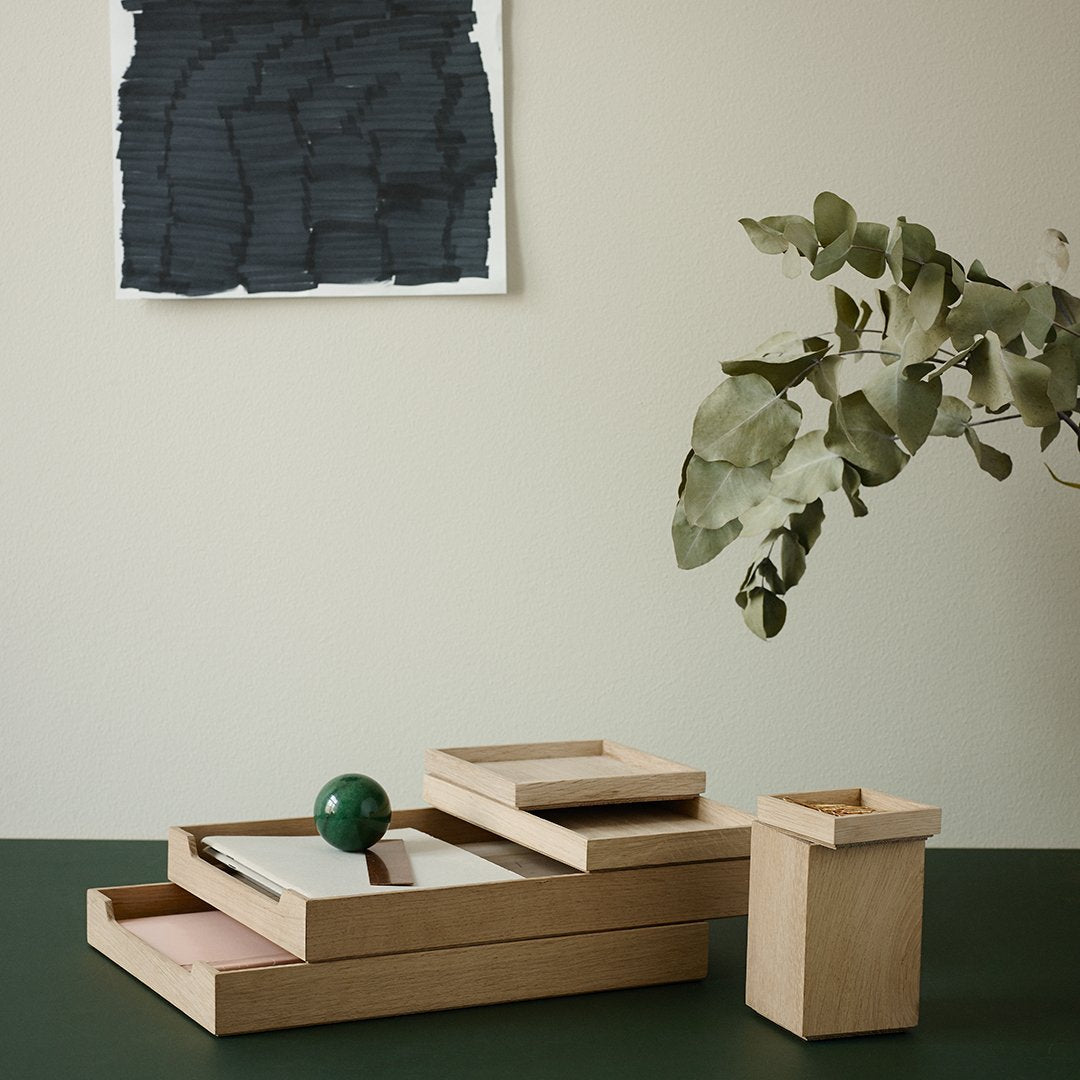 Wooden trays in natural tones with a green decorative sphere, set against a muted backdrop and stylish abstract art.