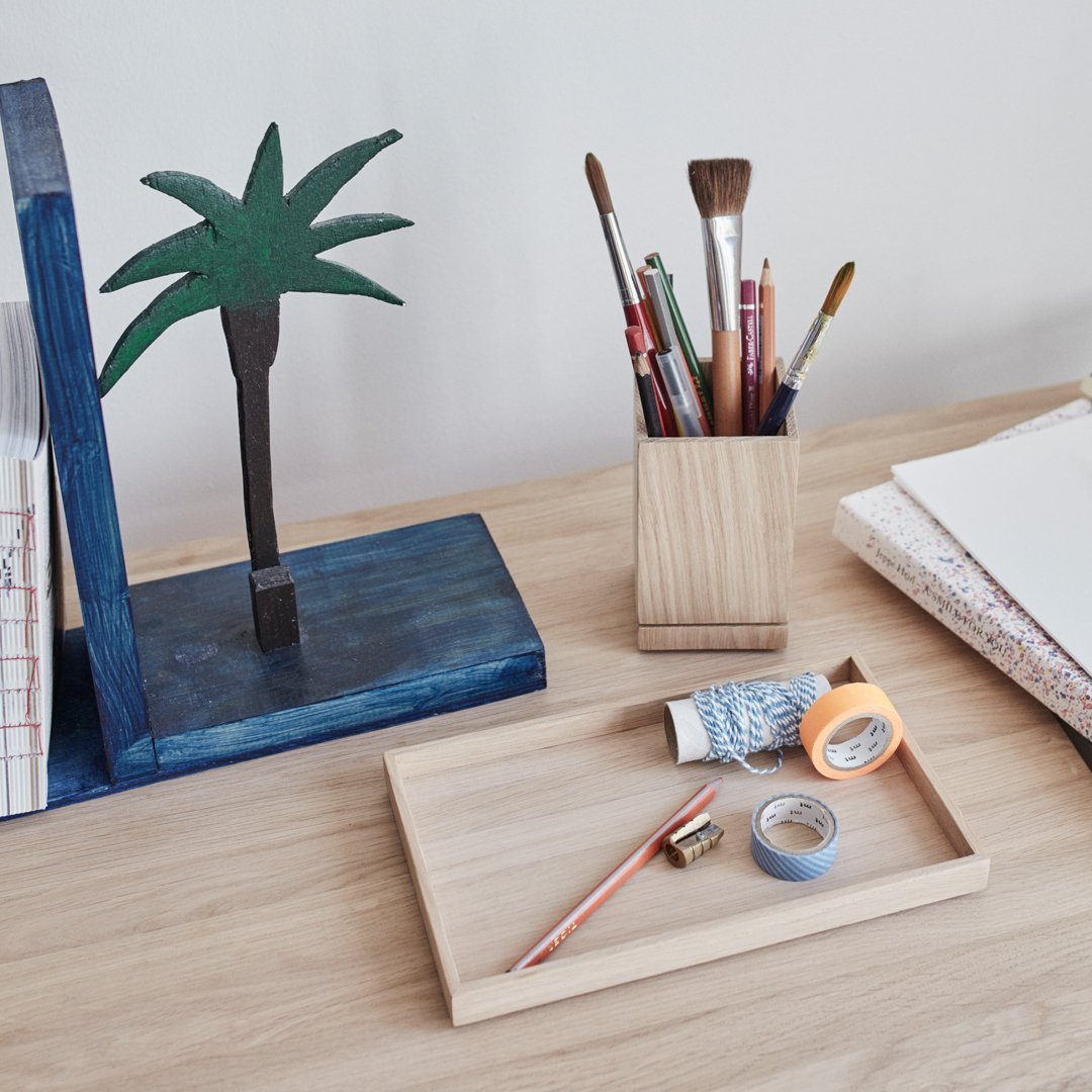 Colorful desk accessories featuring a green palm tree, blue bookends, wooden tray, and various patterned stationery.