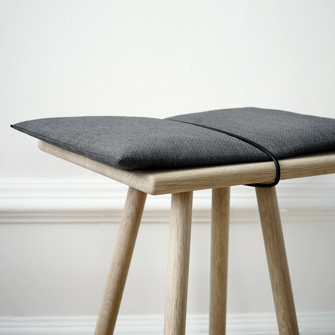 Gray upholstered cushion with a minimalist design, paired with natural wood legs. Perfect for modern decor.