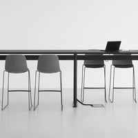 Stylish gray chairs with sleek metal legs at a modern black table on a minimalist white floor.