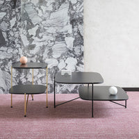Modern black coffee and side tables with gold accents, set against a marble-patterned wall and pink textured rug.