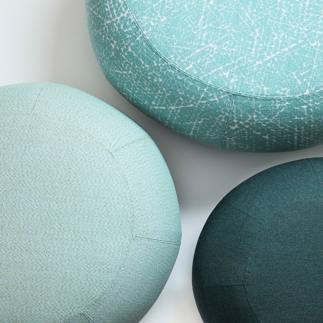 Textured round ottomans in light aqua, teal, and dark green hues with abstract patterns. Perfect for stylish decor.