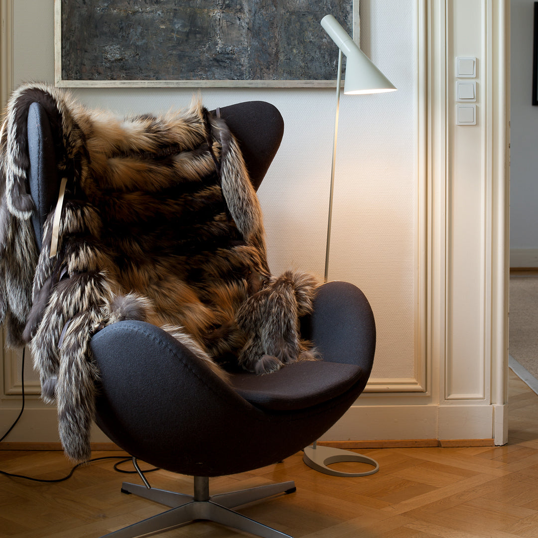 Luxurious brown and tan faux fur throw on a modern black swivel chair, accentuating cozy texture and elegant design.