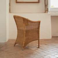 Natural woven rattan chair in warm honey tones with a comfortable, curved design and textured surface.