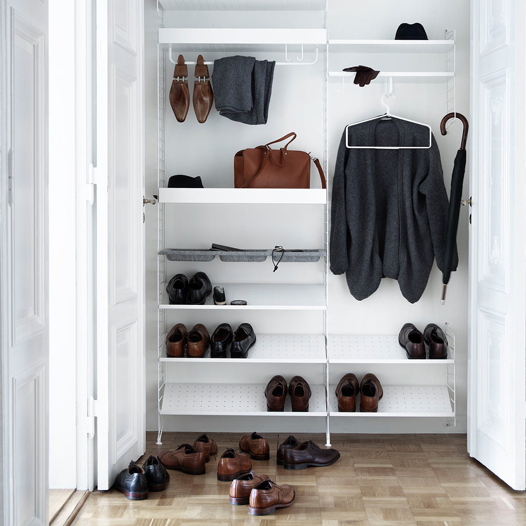 Sleek white shelves with black shoes, grey clothing, and brown accessories in a stylish closet organization setup.