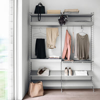 Modern gray shelving unit with a minimalist design, featuring neutral clothing and accessories in soft tones.