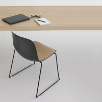 Minimalist black and light wood desk with sleek black and beige chair, featuring smooth lines and modern design.