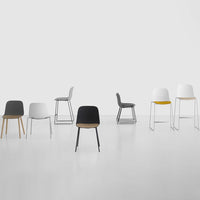 Modern chairs in black, white, gray, and yellow, featuring sleek designs and various leg styles on a minimalist backdrop.