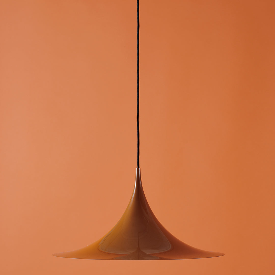 Amber pendant light against a warm orange background, featuring a sleek, modern design. Perfect for contemporary decor.