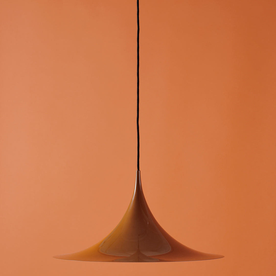 Sleek amber pendant light against a warm orange background, featuring a smooth, modern design.