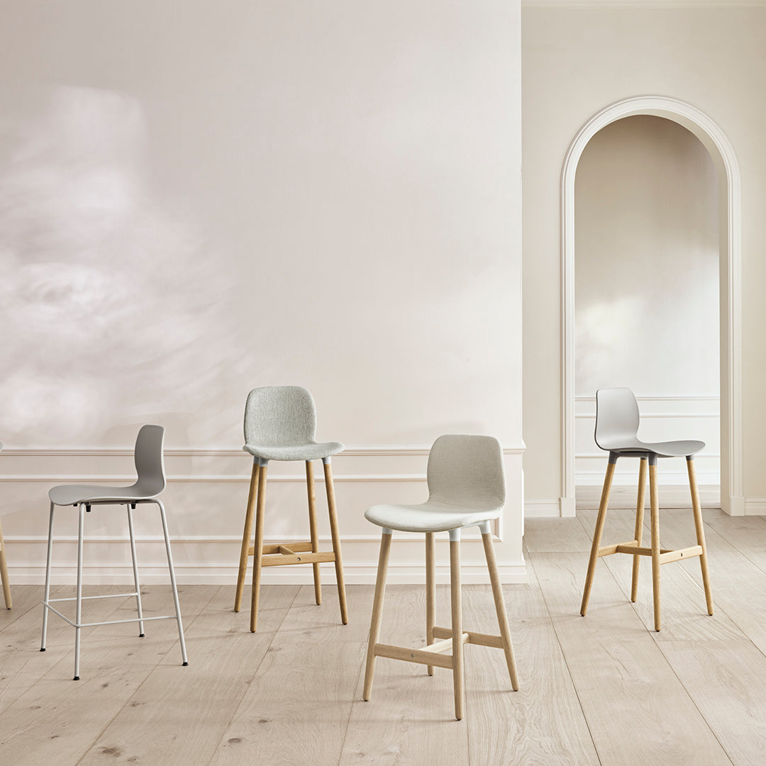 Modern bar stools in soft gray and light beige with natural wood legs, set against a minimalistic, neutral backdrop.