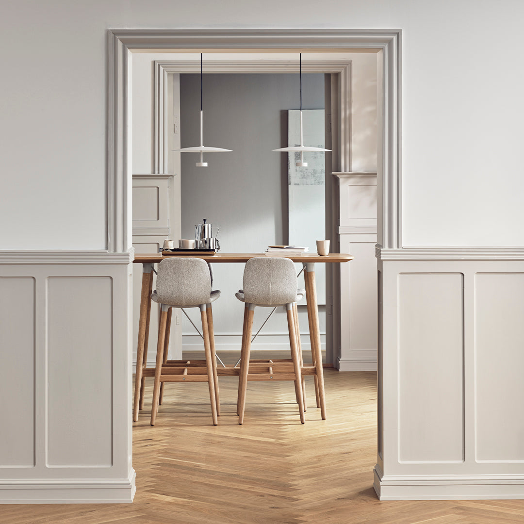 Modern dining space with light gray and white walls, natural wood flooring, and minimalist furniture design.