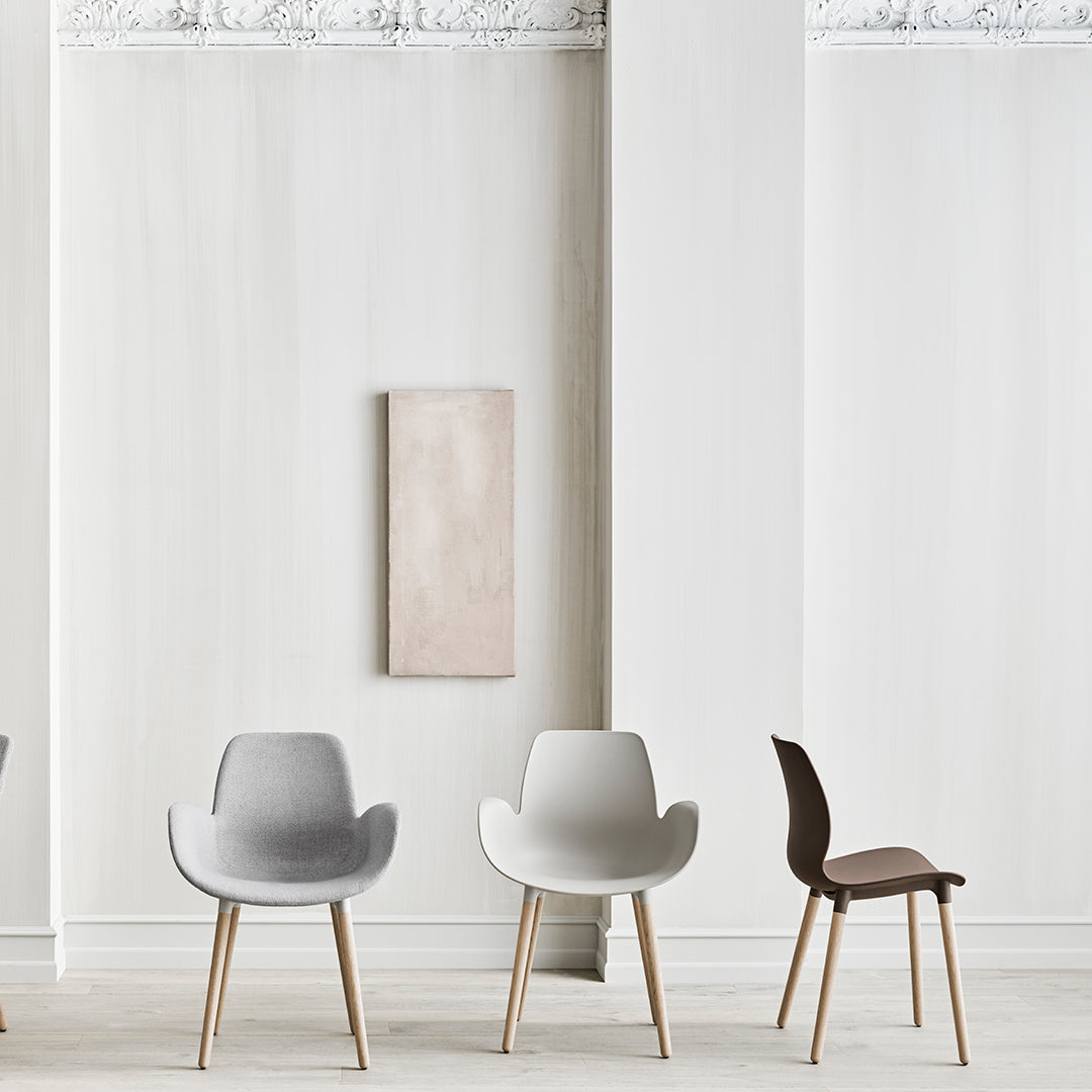 Modern chairs in gray, white, and dark brown, featuring soft textures and clean lines against a minimalist backdrop.