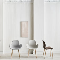 Set of minimalist chairs in light gray, white, and dark brown, featuring natural wood legs against a soft neutral backdrop.