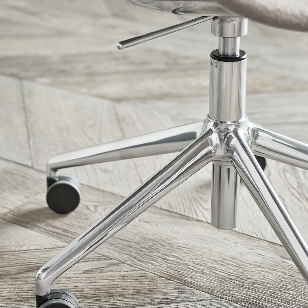 Silver chrome chair base on herringbone-patterned wood floor. Soft beige upholstery adds a modern touch.