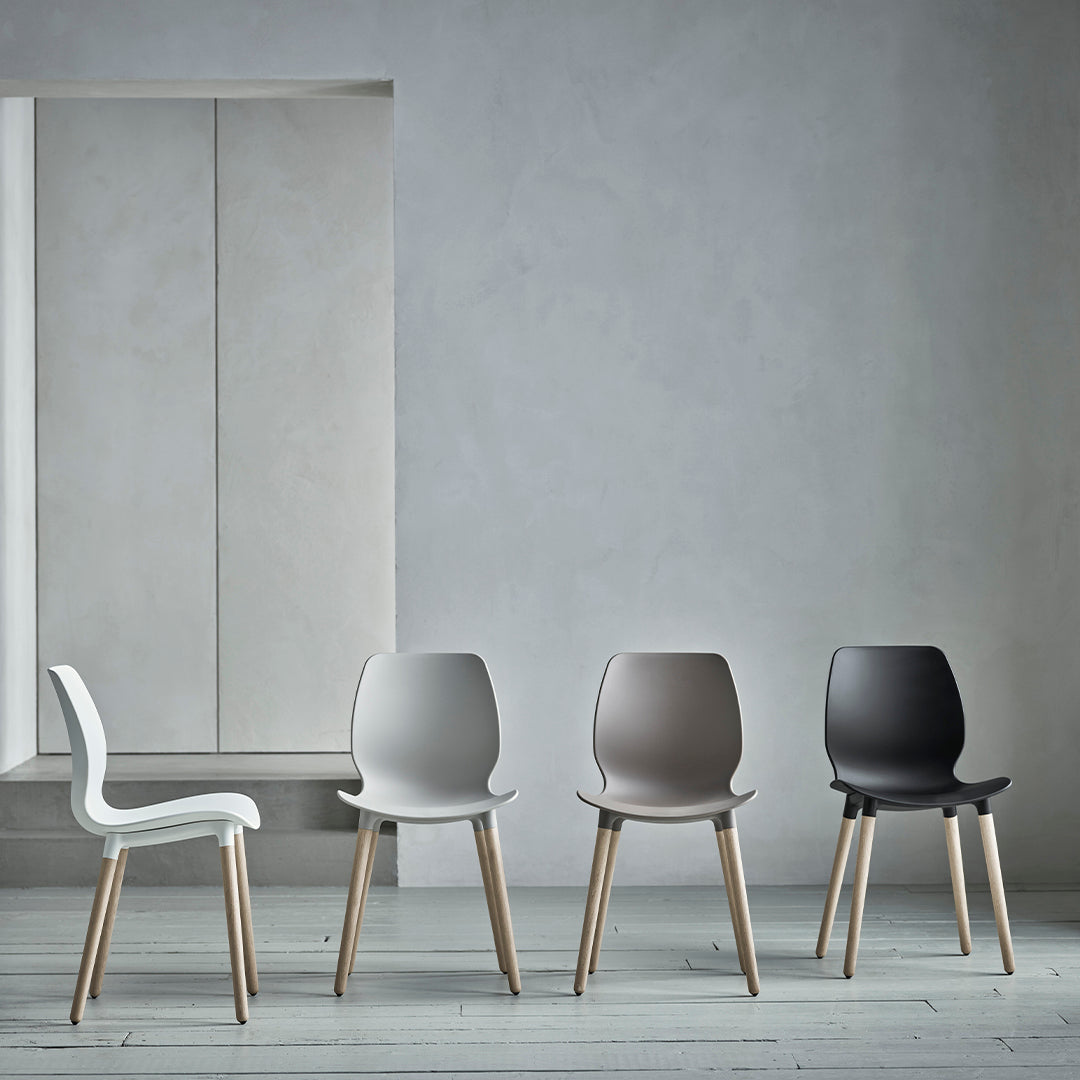 Stylish chairs in white, light gray, taupe, and black, with natural wooden legs, set against a neutral background.