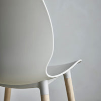 White modern chair with smooth curves and light wooden legs against a subtle gray backdrop.