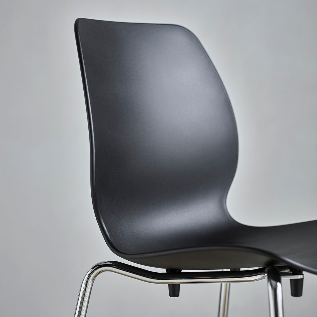 Sleek black chair with a smooth, curved backrest and a minimalist chrome base, showcasing modern design.