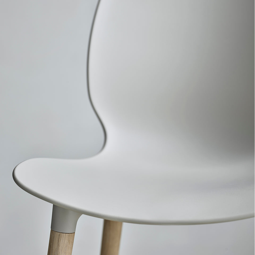 Minimalist white chair with smooth curves and natural wooden legs, ideal for modern decor.