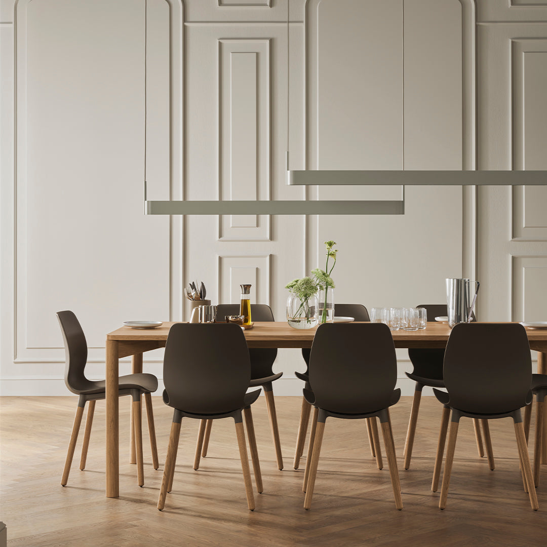 Modern dining room featuring a light wood table, dark gray chairs, and neutral wall tones with subtle patterns.