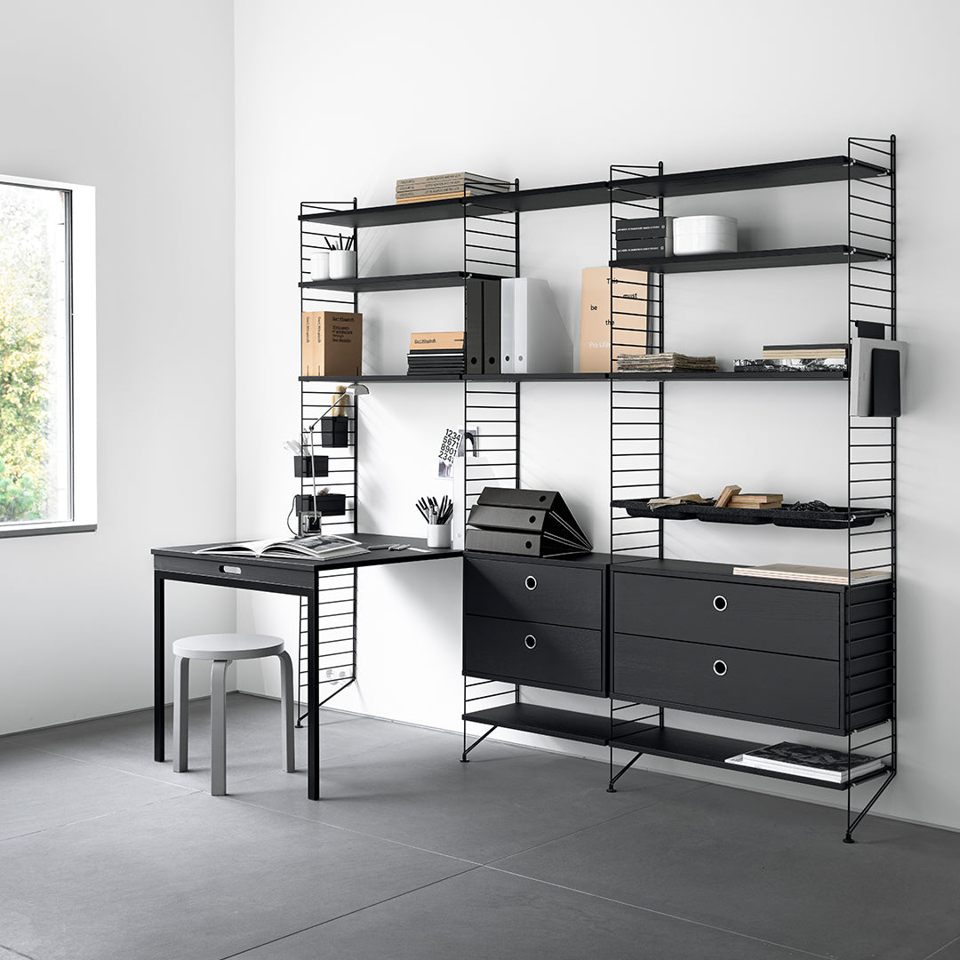 Black metal shelving unit with a simple, modern design; complemented by light wood tones and a neutral gray floor.