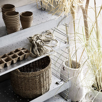 Natural woven basket, neutral tones, earthy clay pots, soft textures, and green plant accents on metal shelves.