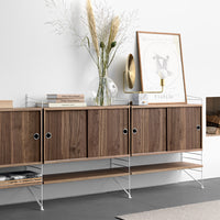 Modern wooden sideboard in rich walnut finish with sleek metal accents and minimalist design against a neutral wall.