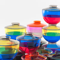 Colorful stacked glass bowls in vibrant hues of blue, pink, green, and yellow with striking striped patterns.