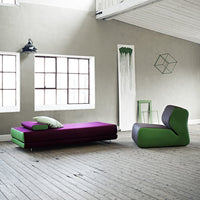 Vibrant purple and green modern furniture set against a minimalist gray wall, featuring clean lines and bold colors.