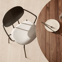 Modern black chair with a gray seat, placed next to a round wooden table with light wood flooring.