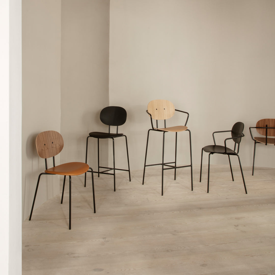 Five minimalist chairs in natural wood tones of tan, brown, and black, set against a light gray background.
