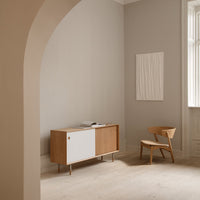 Modern wooden sideboard with white and natural oak accents, set against neutral gray walls and minimal decor.