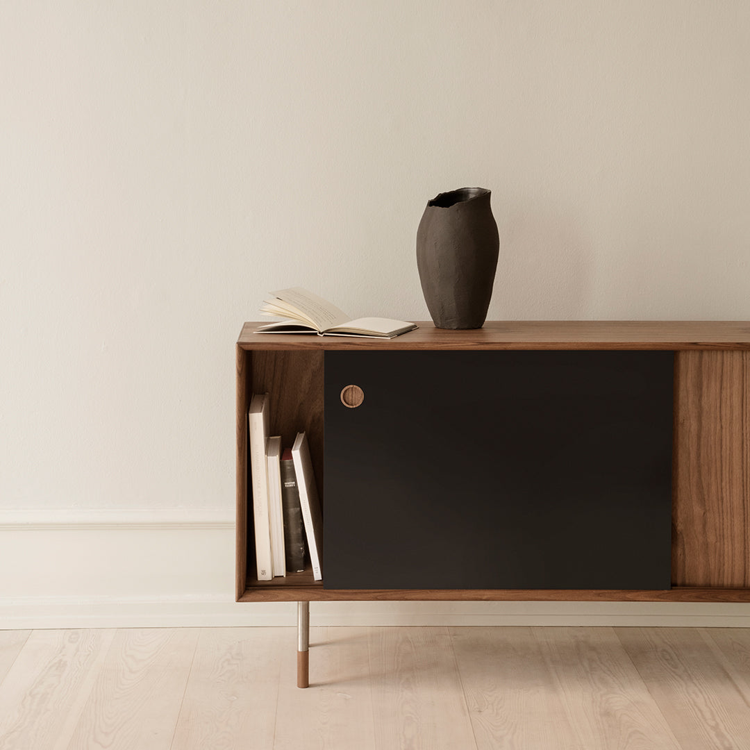 Modern wooden sideboard with a sleek black door and natural wood accents, set against a neutral background.