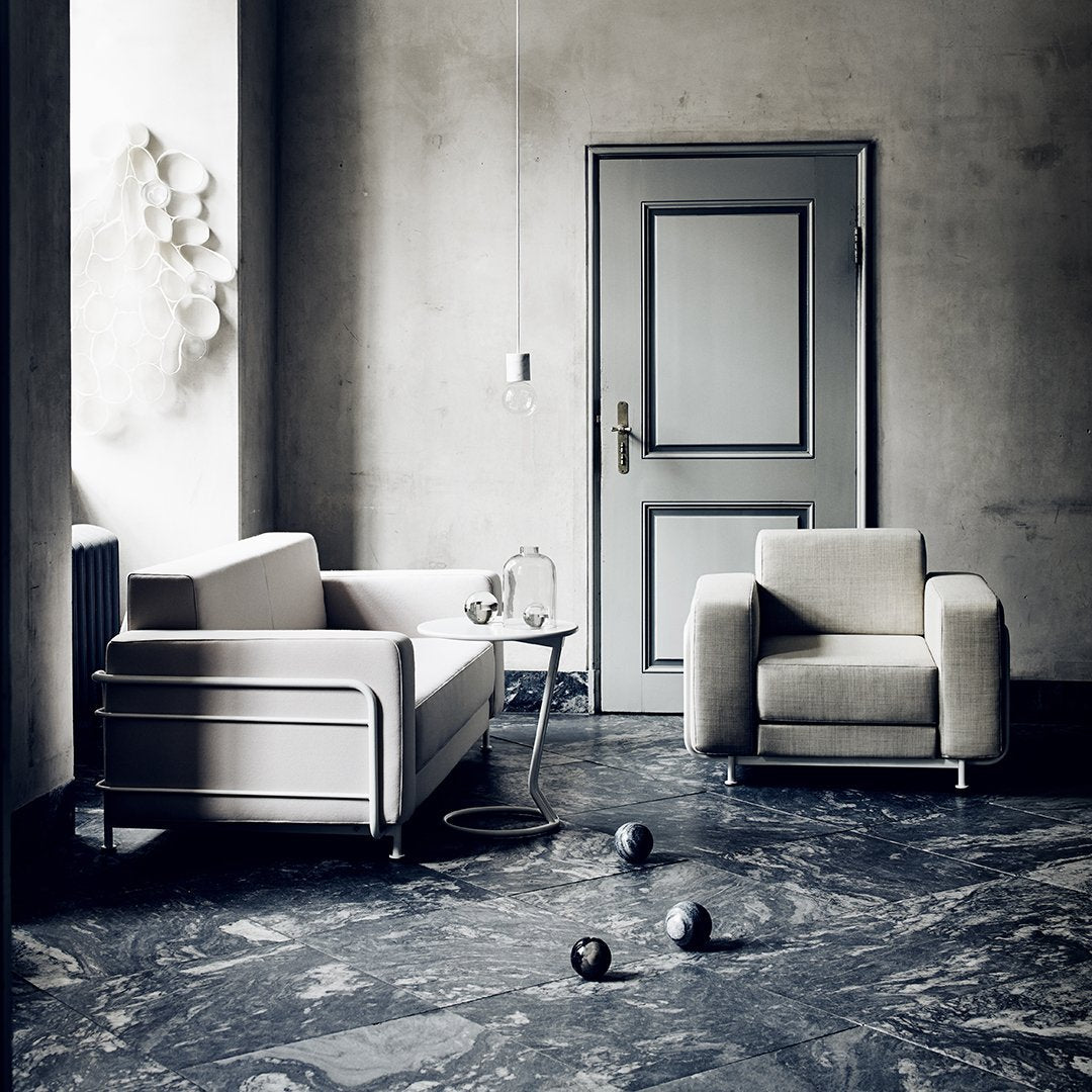 Neutral gray tones dominate the space, with soft beige fabrics and a marbled dark blue floor for a modern, minimalist aesthetic.
