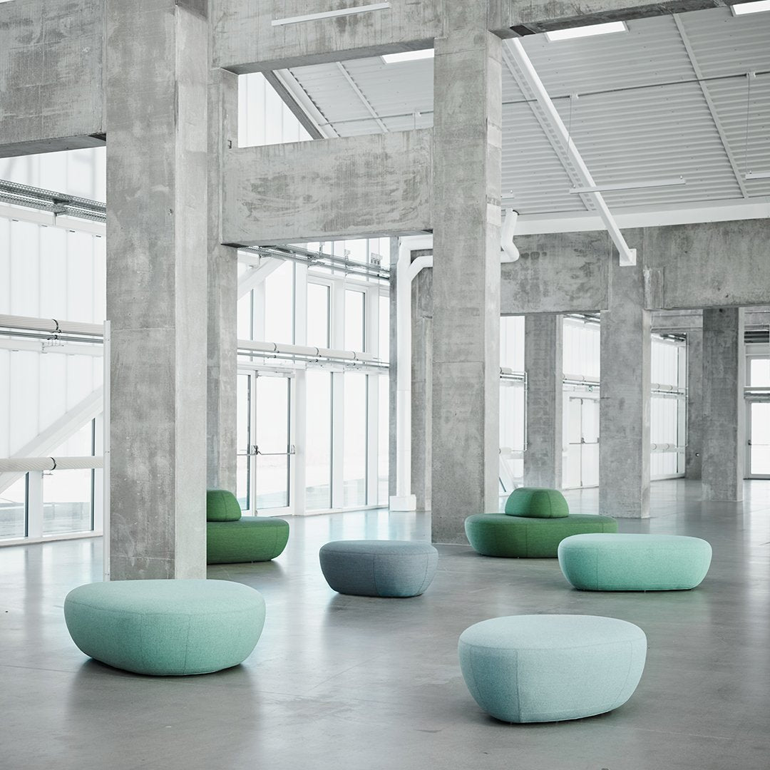 Soft pastel green and blue seating in a modern concrete setting, featuring smooth, rounded shapes and subtle textures.