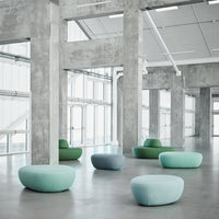 Soft pastel green and blue seating in a modern concrete setting, featuring smooth, rounded shapes and subtle textures.