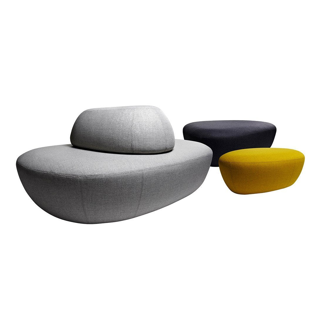 Modern gray sofa with soft curves and yellow and navy accent tables, featuring minimalist design and vibrant colors.