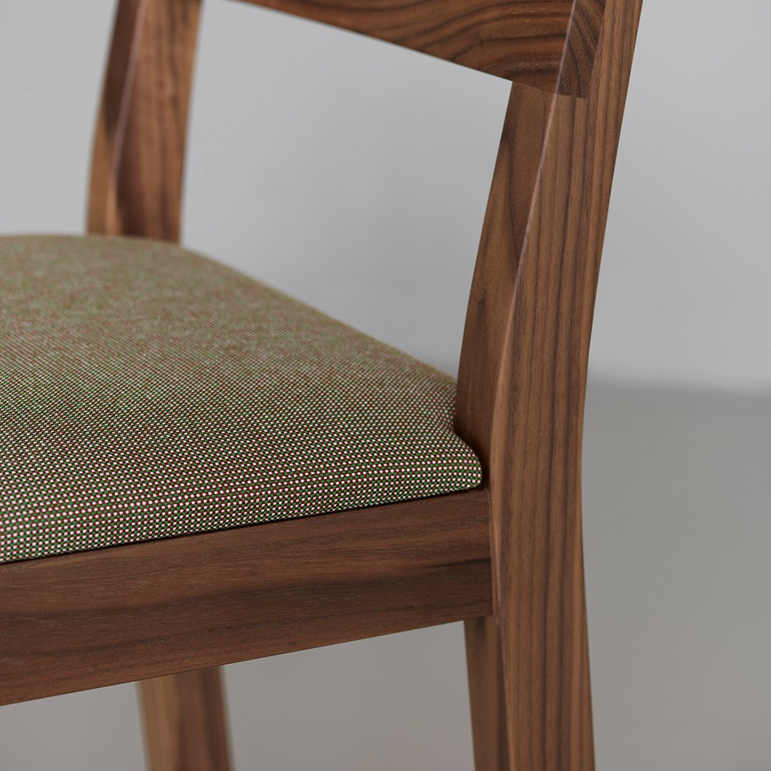 Green patterned upholstery with a subtle check design on a wooden chair. Natural wood finish complements the fabric.
