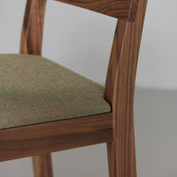 Green patterned upholstery with a subtle check design on a wooden chair. Natural wood finish complements the fabric.
