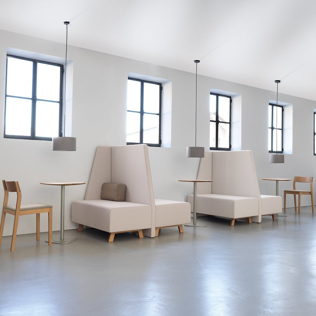 Beige upholstered booths with light wood legs against a minimalist gray floor and bright, airy windows.