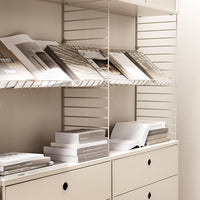 Light beige shelving unit with white books and gray-patterned books stacked neatly. Minimalist, modern design.